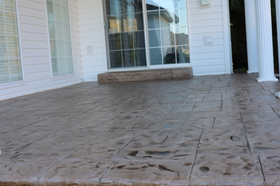 Dark brown paver style stamped concrete patio with a polished finish.