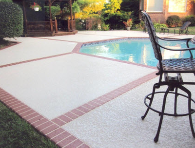 Textured concrete pool deck with brick edging and details.