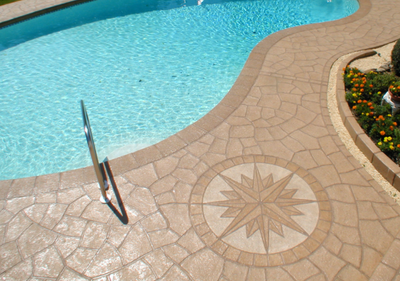 Brown decorative concrete with compass detail around built in pool.