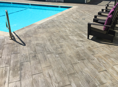 Pool deck with stamped concrete made to look like wood planks.