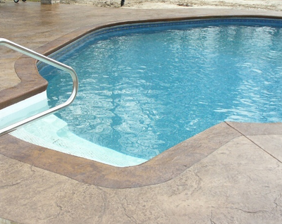 Brown stained and textured concrete around outdoor pool.