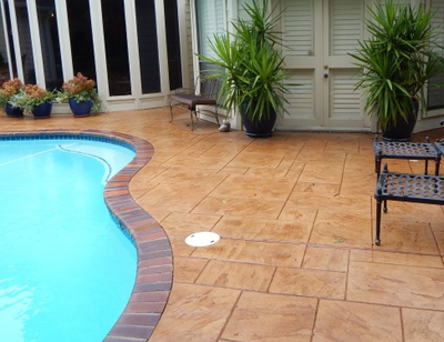 Brown stained and stamped concrete pool deck with brick stamped edging.